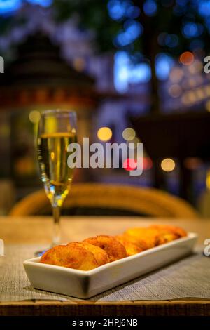Sparkling cava wine, traditional Spanish tapas at an al fresco bar in the center of Madrid Spain and ornate old buildings in the background at sunset Stock Photo