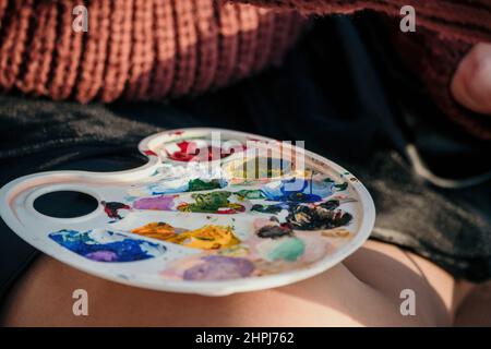 A woman's hands mixing paints on a palette board. Preparing to paint a picture. Artistic tools. The creative process. Stock Photo