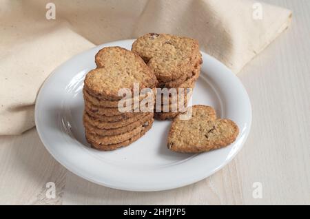 Oatmeal cookies in the shape of a heart in plate on light wooden table Stock Photo