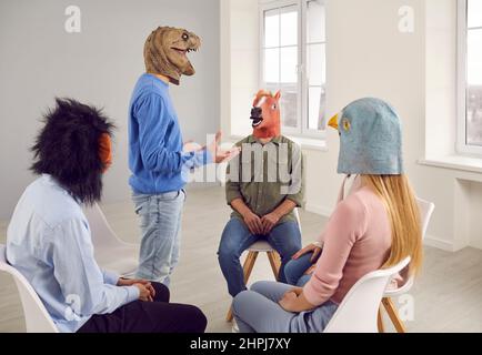 People in funny animal masks having a conversation during a group therapy session Stock Photo