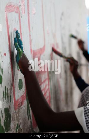 Schoolchildren paint the walls of their school hall at Macheke Primary School. The children were given free reign to draw anything they wanted. Zimbabwe. Stock Photo