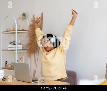 African-american female stretching after working on laptop. Listening to music in earphones Stock Photo