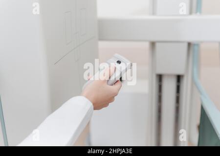 Hospital Radiology Room. Xray fluorography device remote control. Doctor radiologist in gown adjusting the X-ray machine for radiography. Medical Stock Photo