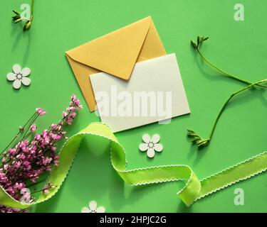 Spring background in shades of green and yellow. Paper envelope with pink flowers on green paper background. Stock Photo