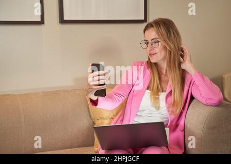 Pretty businesswoman using smartphone to take picture of self Stock Photo