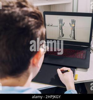Young student male 3D designer uses graphics tablet to work at his desk. development of 3d characters for online games. Stock Photo