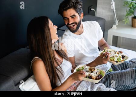 Healthy breakfast in bed. Young beautiful couple in love is sitting on bed and having breakfast. Stock Photo