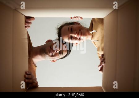 Low angle view of happy young couple opening the box and looking down with smile, they happy to get parcel Stock Photo
