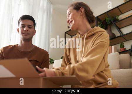 Young couple talking to each other and packing things together in the box sitting in the room Stock Photo