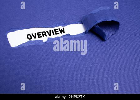 The text OVERVIEW appearing on whitepaper behind torn blue paper. Stock Photo