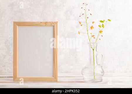 Wooden frame with orange barrenwort flowers in glass on gray concrete background. side view, copy space, still life, mockup, template, spring, summer Stock Photo