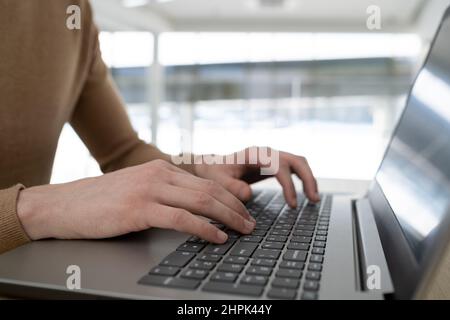 Hands of contemporary ceo or entrepreneur typing on laptop keyboard while sitting by workplace and working over new project or analyzing data Stock Photo