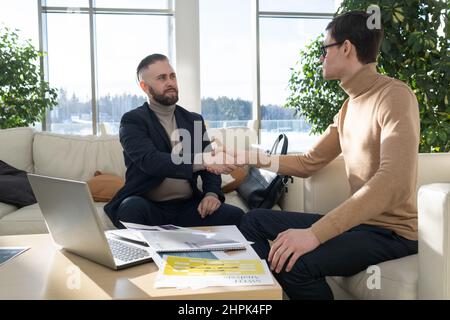 Contemporary entrepreneur or ceo hiring new employee in high tech corporation and shaking his hand after talk and interview Stock Photo