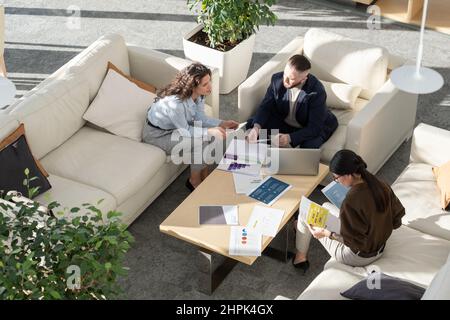 Young female manager of high tech corporation making report about web analytics and statistics to ceo by workplace at meeting Stock Photo