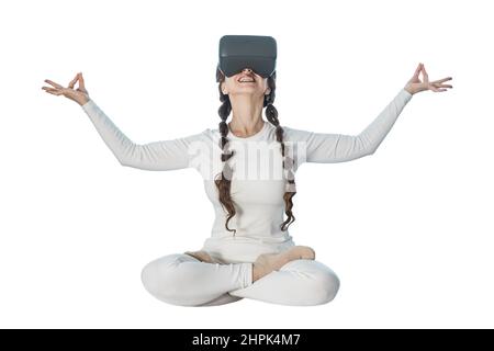 A woman does yoga with virtual reality glasses. She takes various yoga poses and smiles. Stock Photo