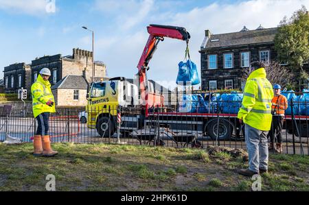 Trinity Primary School, Edinburgh, Scotland, UK, 22 February 2022. Botanics Topsoil for Schools: excavation during the Royal Botanic Garden Biomes Project results in a 50 tonne topsoil surplus which is being given to schools, allotments & community organisations by construction company Balfour Beatty. A 5 tonne delivery takes place at Trinity Primary School to carry soil or earth to fill planters in the school garden for pupils to grow vegetables. Primary 4 pupils use containers of all shapes & sizes to move earth to fill the planters; team work is required Stock Photo