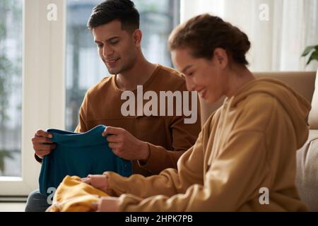 Young smiling couple looking at new clothes in their hands, they getting the parcel by delivery Stock Photo
