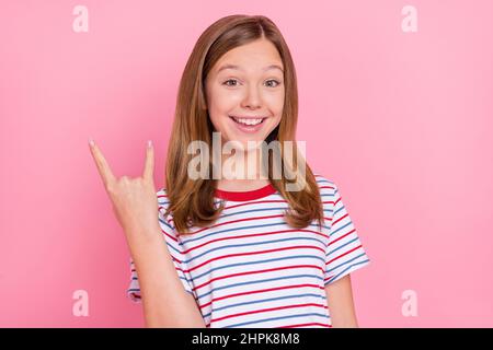 Photo of cool small blond girl show rock sign wear red t-shirt isolated on pink background Stock Photo