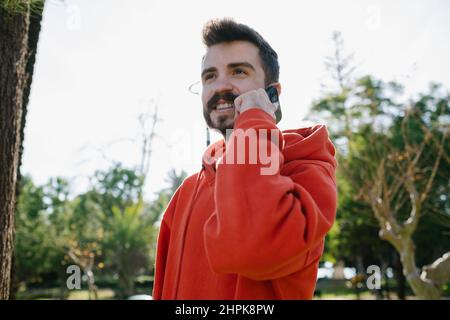 Talking phone, happy young man looking aside while talking by his phone. Handsome man laughing with talking his girlfriend. Cheerful male talking with Stock Photo