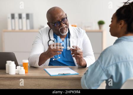 Experienced black doctor explaining treatment plan to patient Stock Photo
