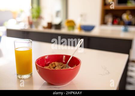 Close-up of orange juice with cornflakes bowl on table in kitchen at home Stock Photo