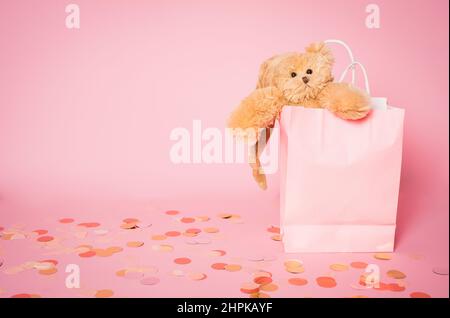Teddy bear in pink paper bag isolated over pink background. Stock Photo
