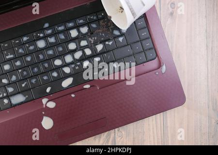 tea spilling over a laptop keyboard on table  Stock Photo