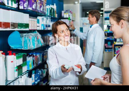 Smiling female pharmacist wearing uniform working Stock Photo