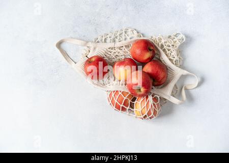 Fresh red apples in a hand bag on a gray background. Top view Stock Photo