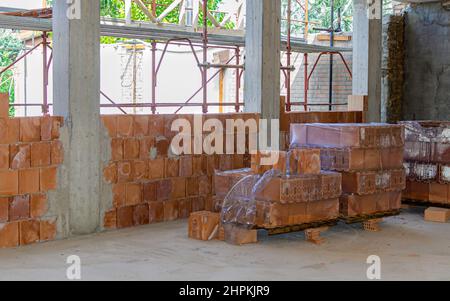 Stack of brick bricks, shovel, broom and other work tools of a bricklayer on a construction site Stock Photo