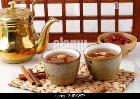 Sujeonggwa, Korean Traditional Cinnamon Punch. Dark Reddish Brown in Color, it is Made from Cinnamon Stick, Gotgam, and Ginger and is Garnished with P Stock Photo