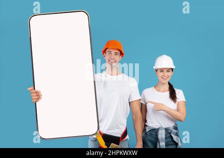 Two Construction Workers In Helmet Holding Showing Big Cellphone Screen Stock Photo