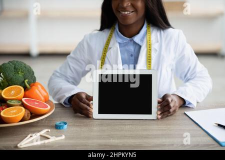 Cropped of african american female dietologist holding digital tablet with blank screen, mockup Stock Photo