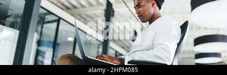 Coding expert working on a new project in a modern office. Creative businessman using a laptop while sitting in a modern workplace. Focused young busi Stock Photo