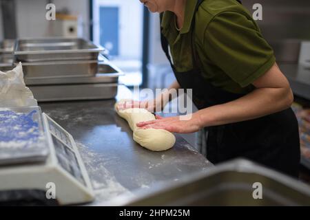 An unrecogniozable chef kneading yeast dough indoors in restaurant kitchen. Stock Photo