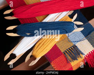 Four shuttles with bright colored yarns for creating a tapestry. Weave of threads of four colors, close up Stock Photo