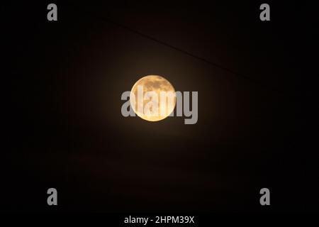 Close up shot of full moon set against dark black night sky. Electric wires, city at night Stock Photo