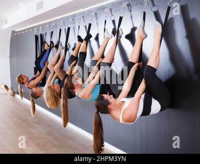 Group of sporty girls practicing wall yoga poses with straps in modern yoga  studio Stock Photo - Alamy