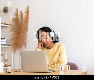 Bored african-american female student sleeping during online classes on laptop at home Stock Photo