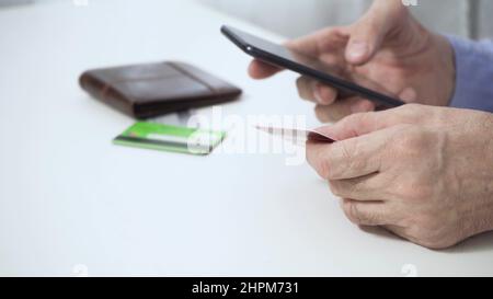 The hands of a man who, holding a smartphone, a credit card, makes a successful payment. Stock Photo