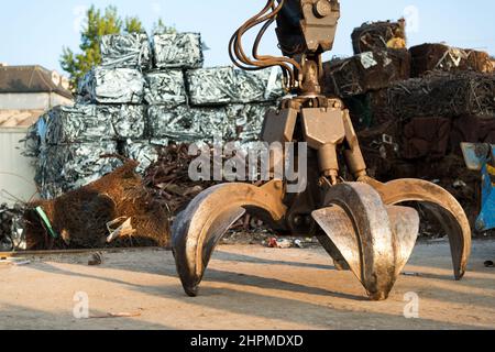 Large tracked excavator working a steel pile at a metal recycle yard. Industrial scrap metal recycling - selective focus, copy space Stock Photo