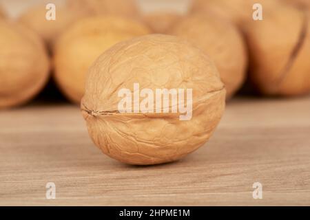 One nut in the foreground the others in the background lie on a wooden table Stock Photo
