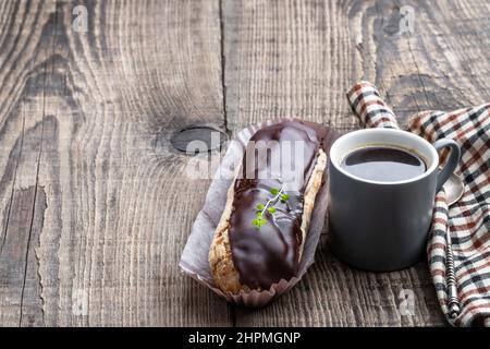 Glazed  eclairs with a cup of coffee on wooden table Stock Photo