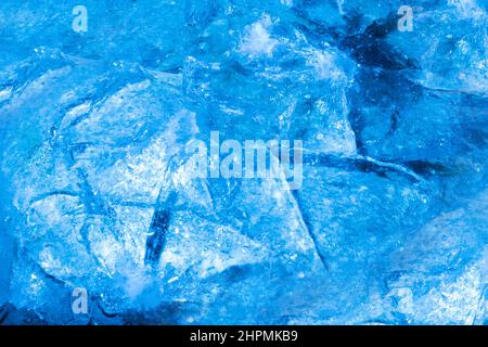 Close up photo of blue toned frozen cracked and damaged ice surface texture. Stock Photo