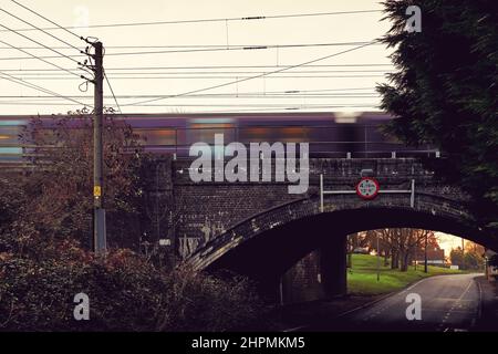 East Midlands Railway regional diesel multiple train speeds across an old road bridge with height restriction at Sharnbrook, Bedfordshire, England, UK Stock Photo