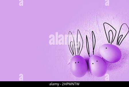 easter colored eggs with bunny ears on purple background. Stock Photo