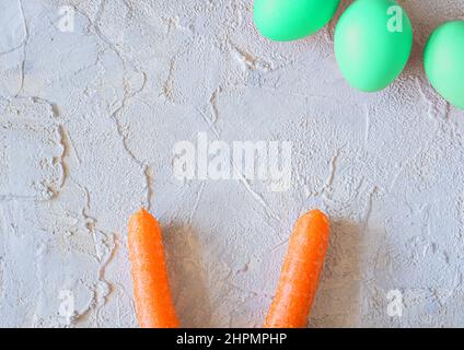 easter colored eggs with bunny carrot ears on light textured background. Stock Photo