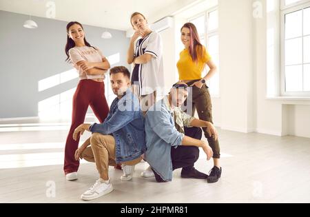 Young hip hop dance crew members in casual clothes posing in their dancing studio Stock Photo