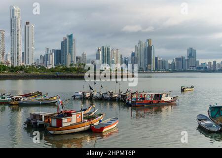 Fishing boats docked in front of modern skyscrapers in Casco Viejo Panama City. Hazy day with calm waters. Stock Photo