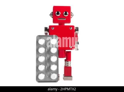 Isolated photo of red colored metal miniature robot toy standing with pills blister on white background. Stock Photo